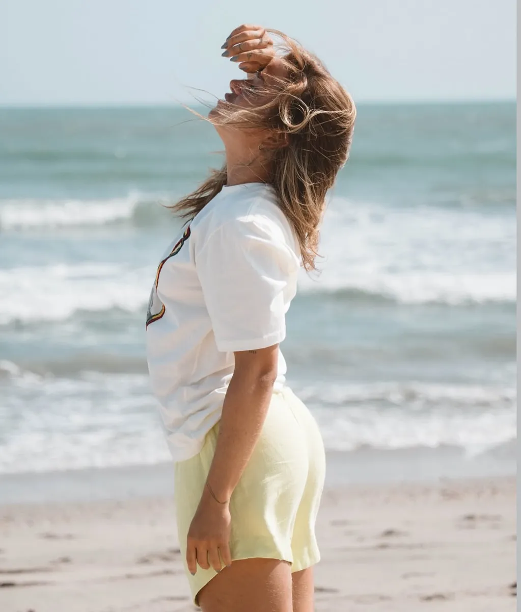 Mulher de costas para o mar, cabelo ao vento, na areia do Preá
